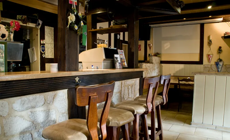 Theke mit Barhockern, Natursteinwand und Vereinswimpeln